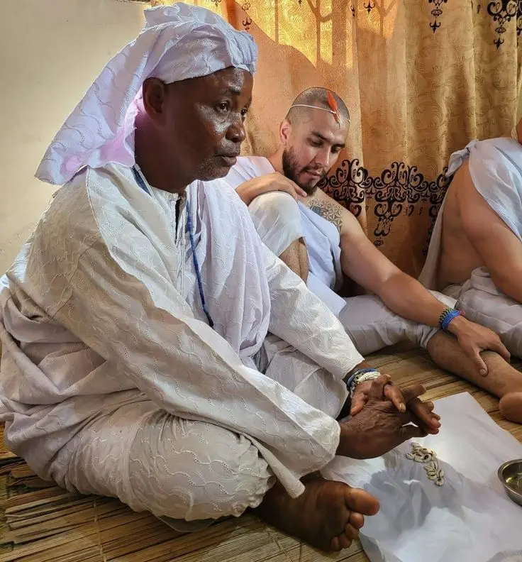 Dr Abdul in white robes, seated on a mat with clients during a consultation