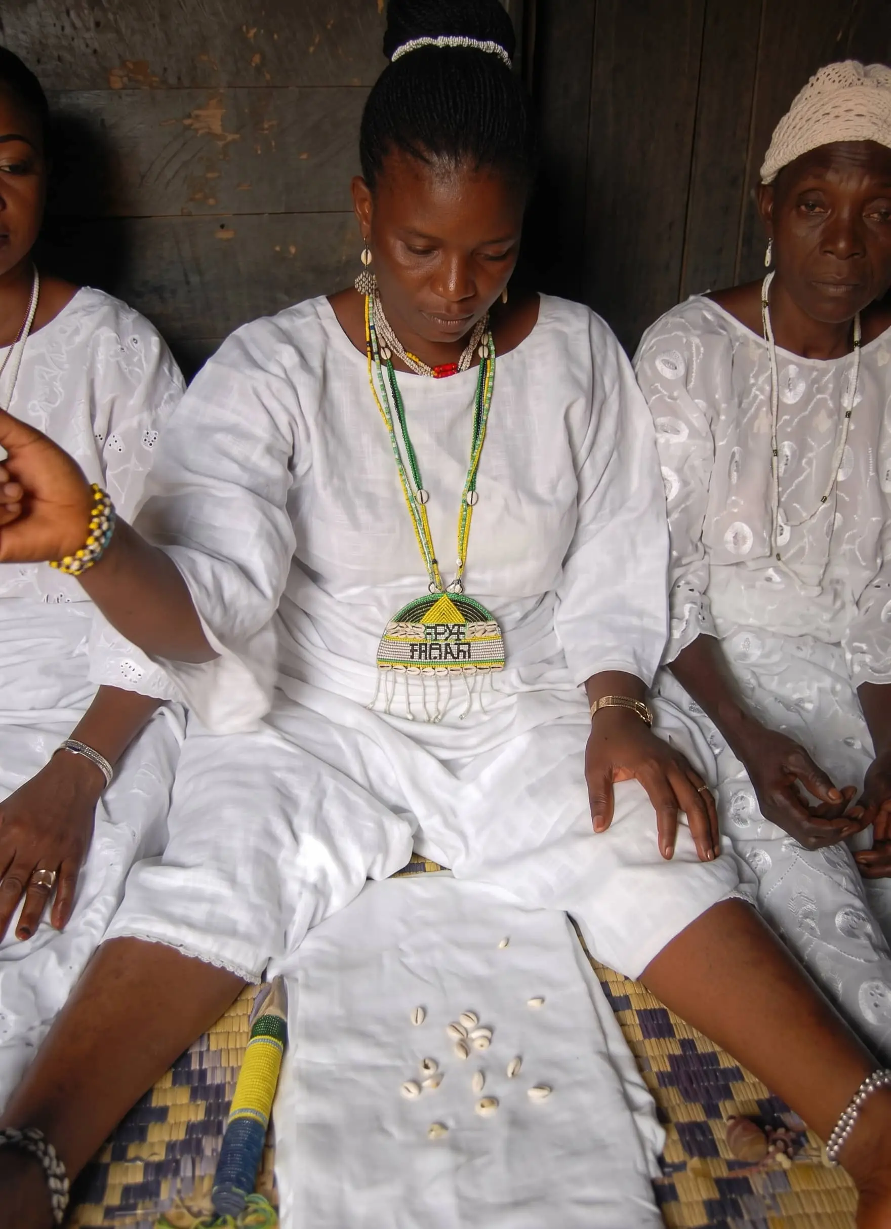 Mama Nangobi in white, seated with clients during a traditional ceremony